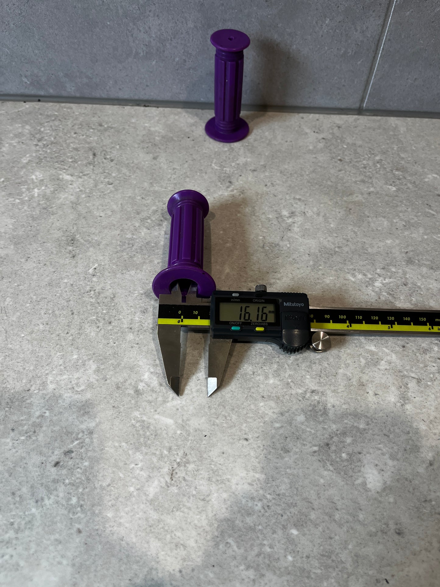 Purple rubber handlebar grip measured with a digital caliper at 16.16mm.