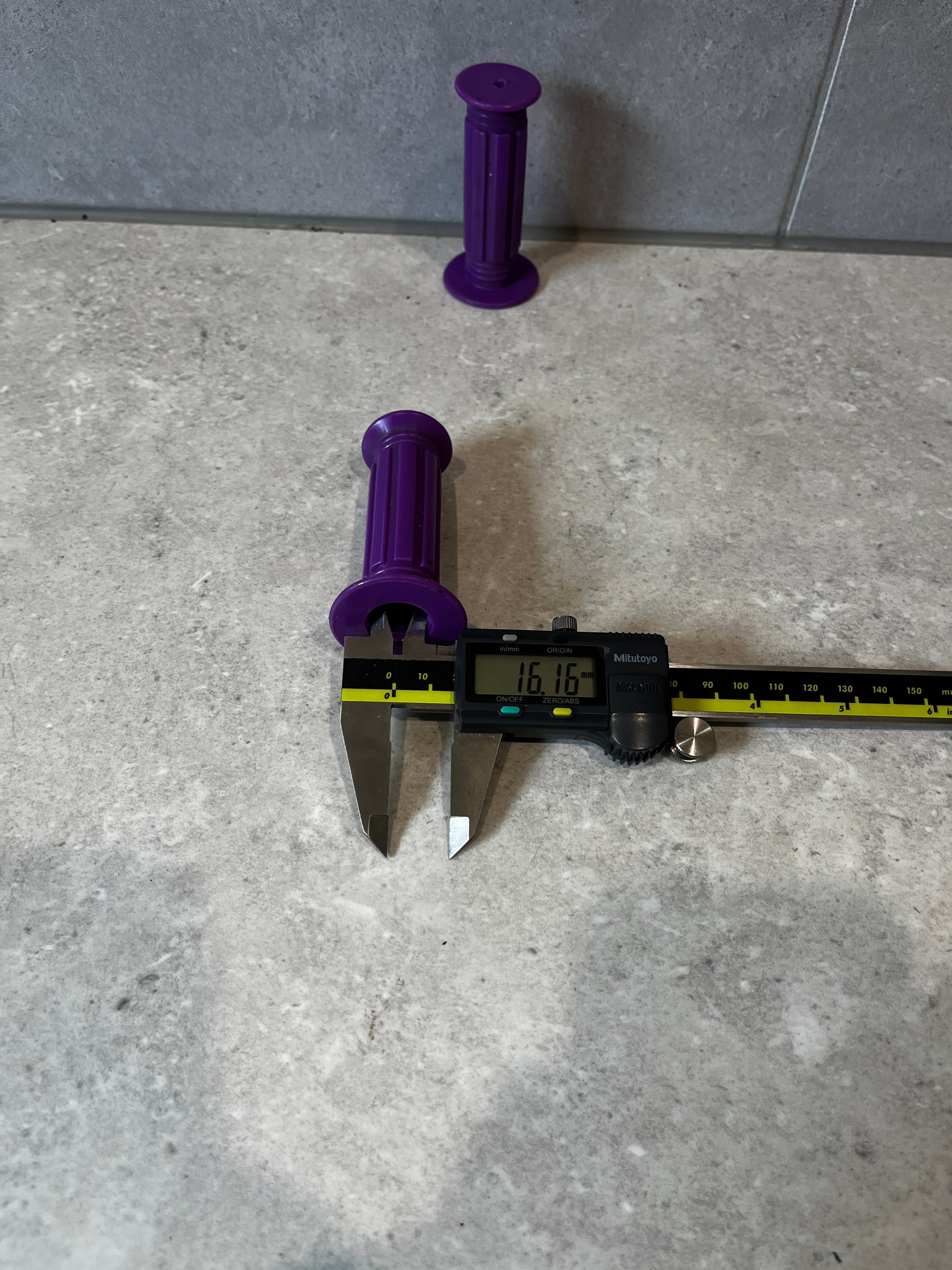 Purple rubber handlebar grip measured with a digital caliper at 16.16mm.