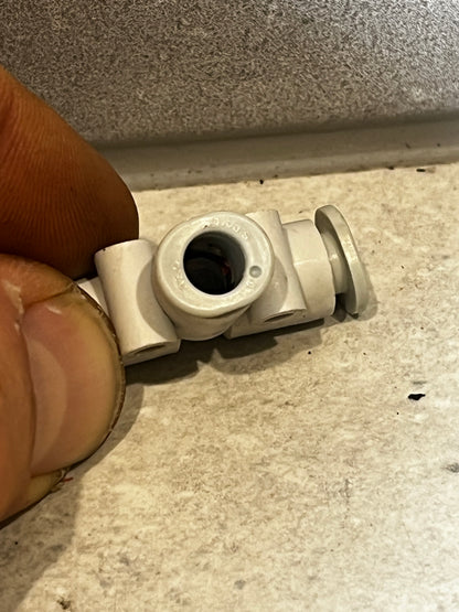 Close-up of plastic pneumatic tube tee fitting connector held by hand