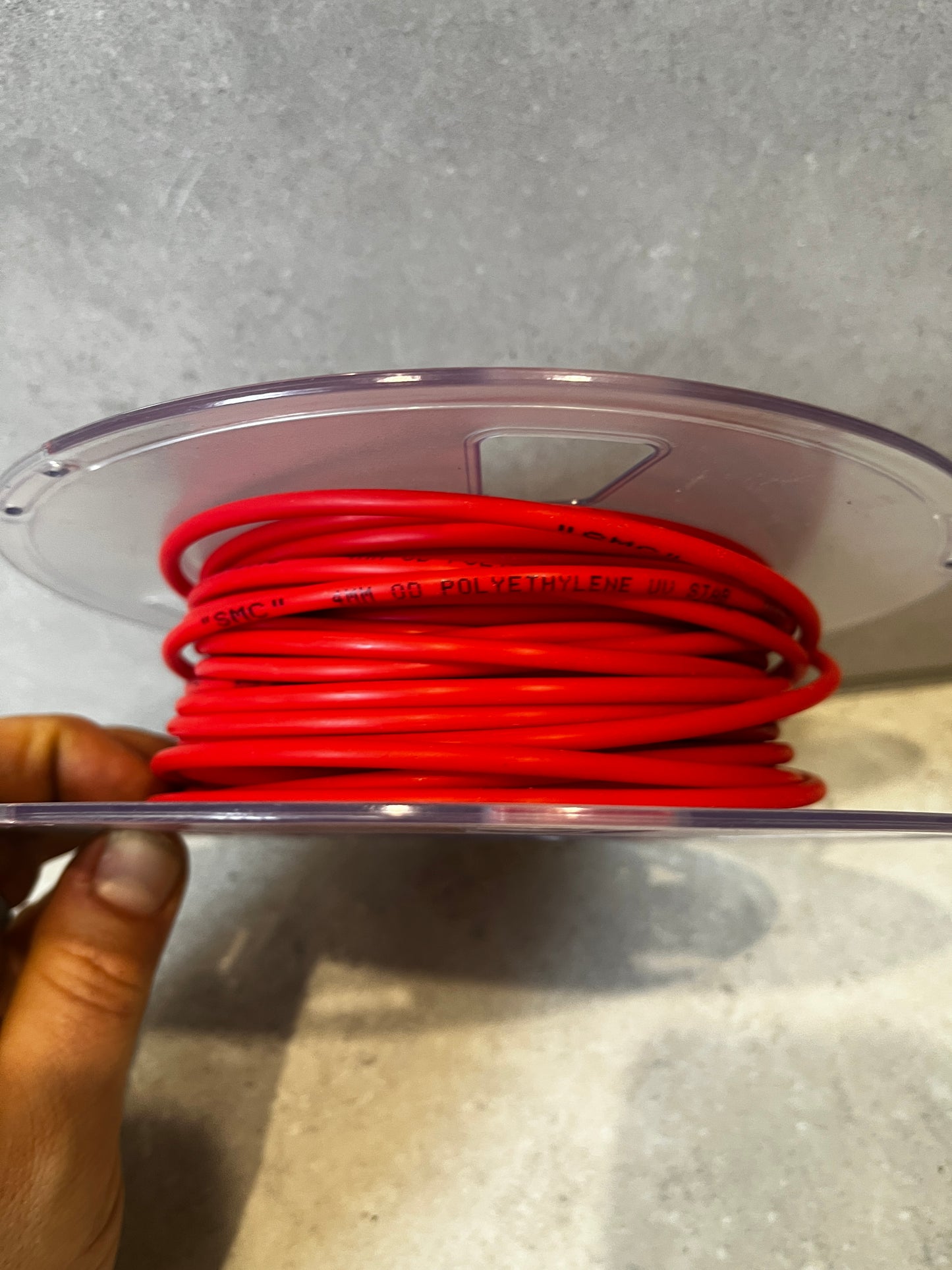 Side view of red polyethylene tubing coiled on a spool