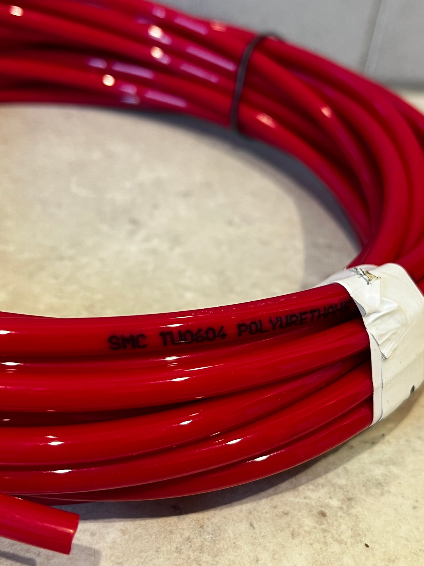 Close-up of red polyurethane tubing with printed label SMC TL0604 POLYURETHANE