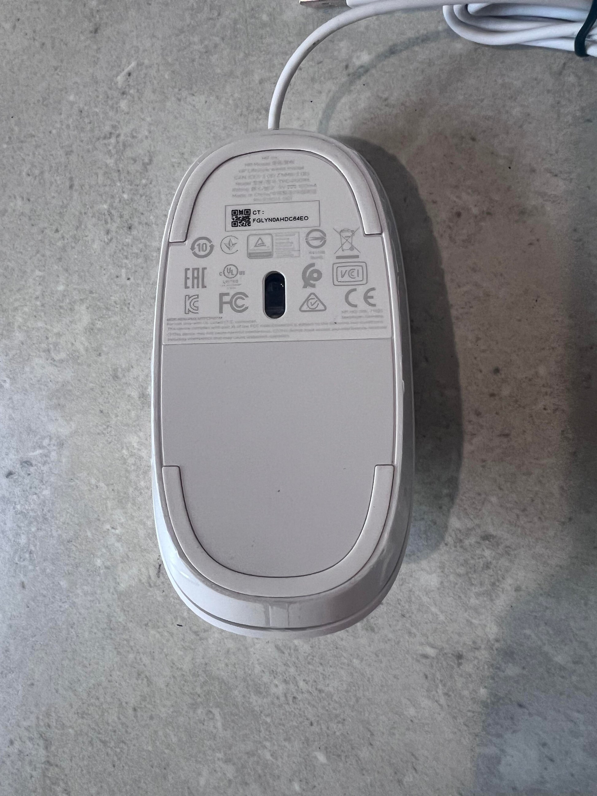 Bottom view of white HP optical mouse showing sensor and product labels