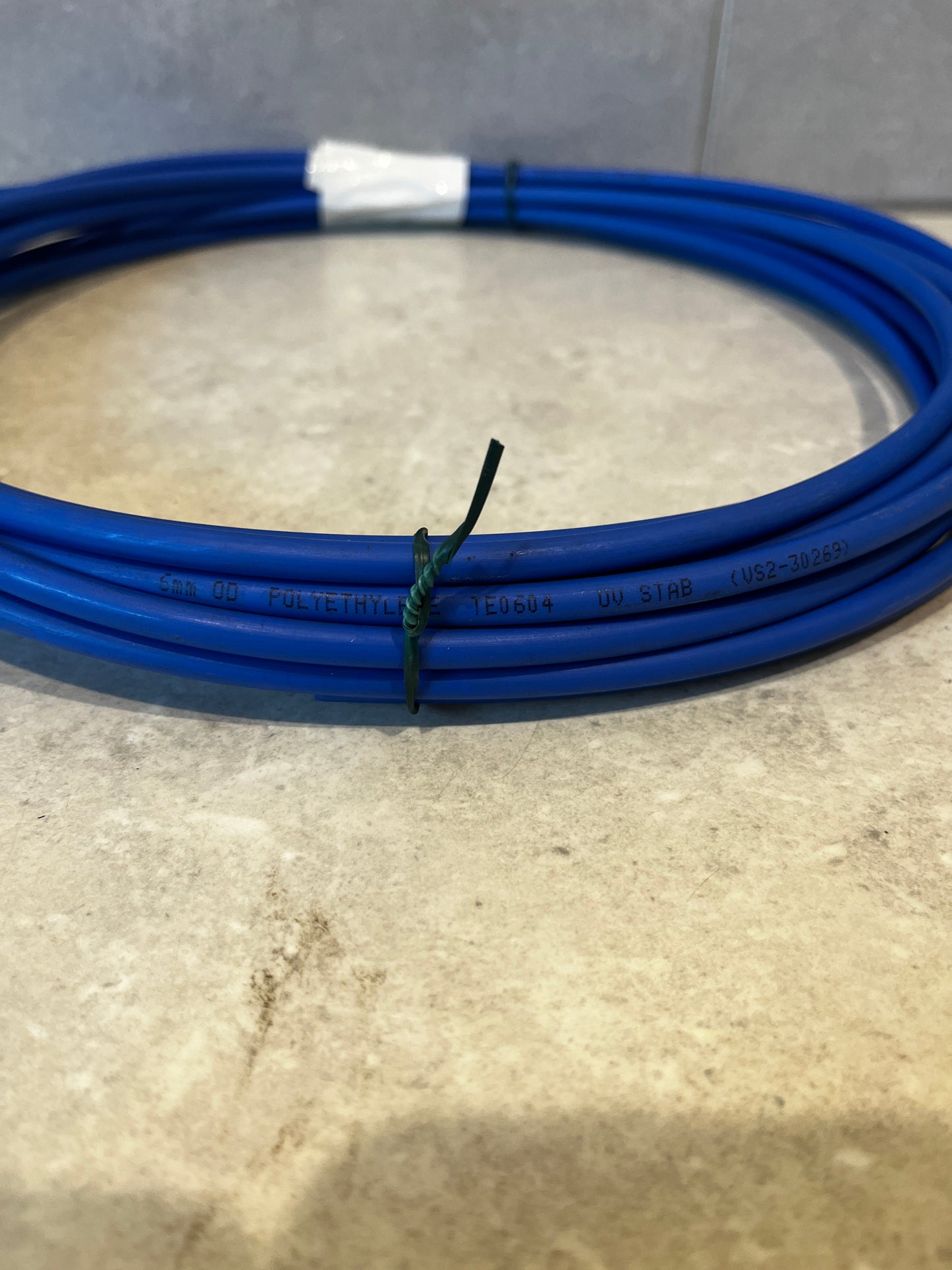Close-up of blue polyethylene tubing showing UV stabilized marking and 5mm diameter