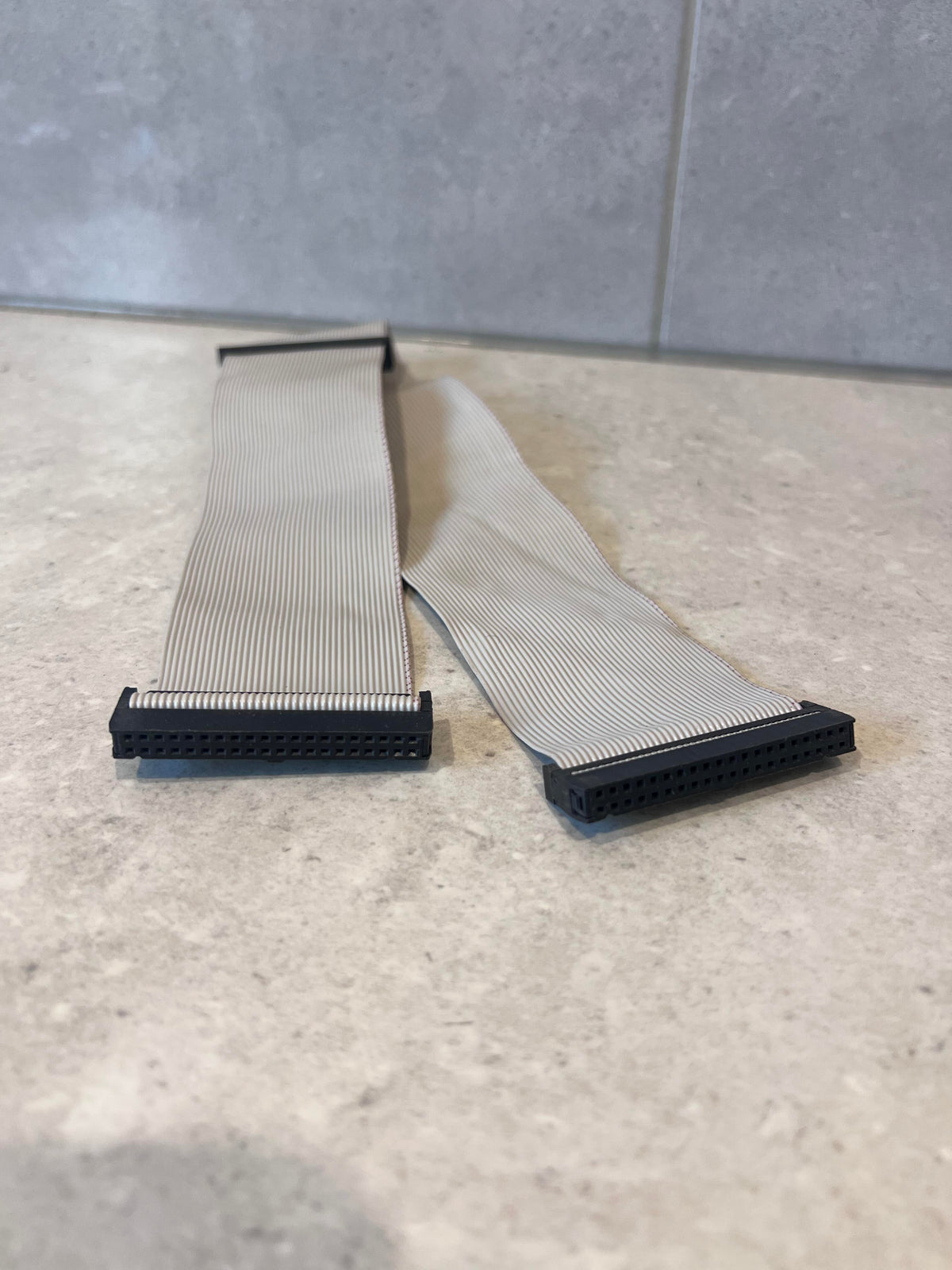 Close-up of both ends of 40-pin IDC ribbon cable with black connectors