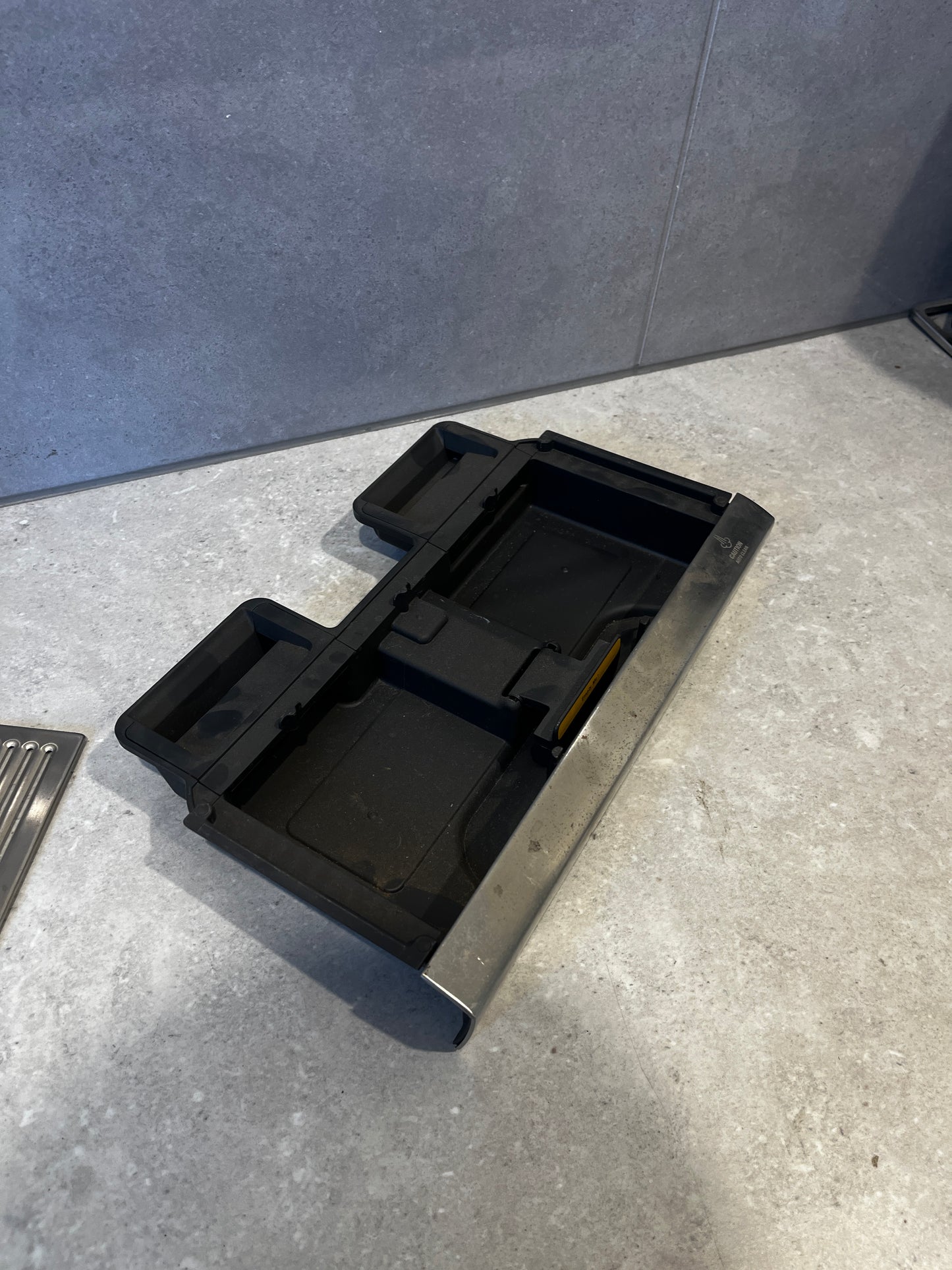 Bottom view of removable black plastic drip trays from the stainless steel espresso drip tray.