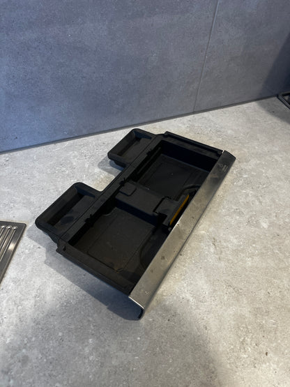 Bottom view of removable black plastic drip trays from the stainless steel espresso drip tray.