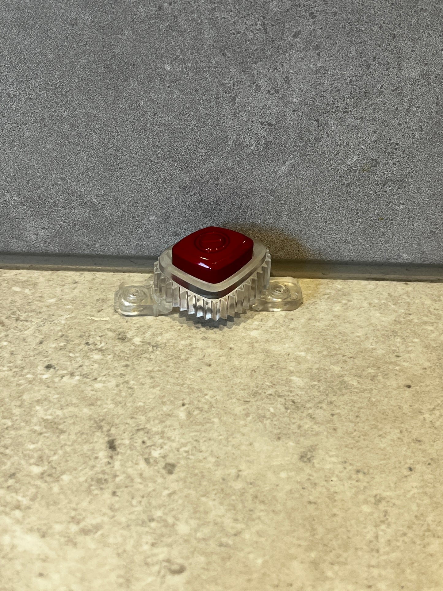 Single red mechanical keyboard keycap mounted in a transparent base