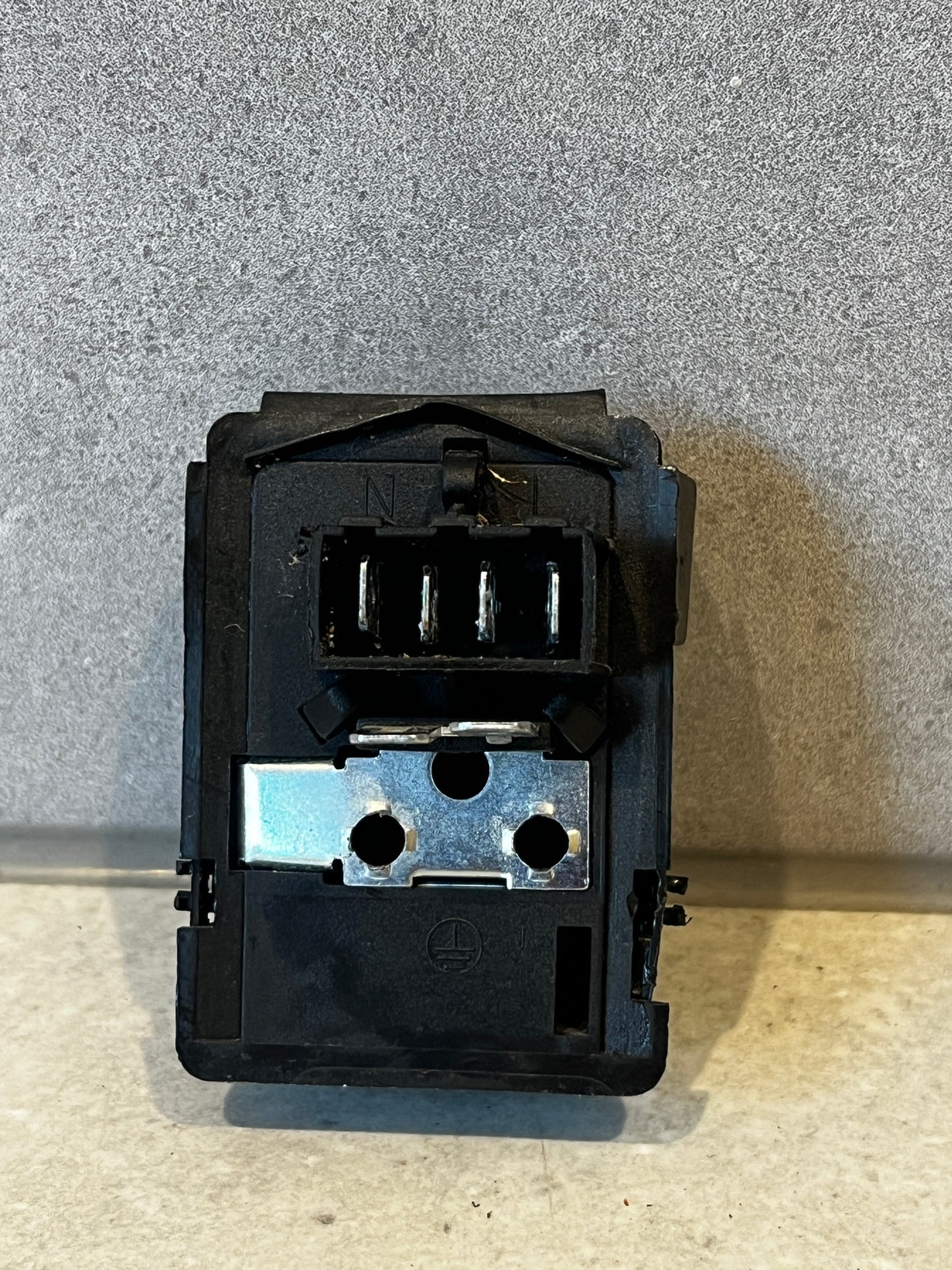 Rear view of black electrical relay switch showing metal connectors and terminal slots