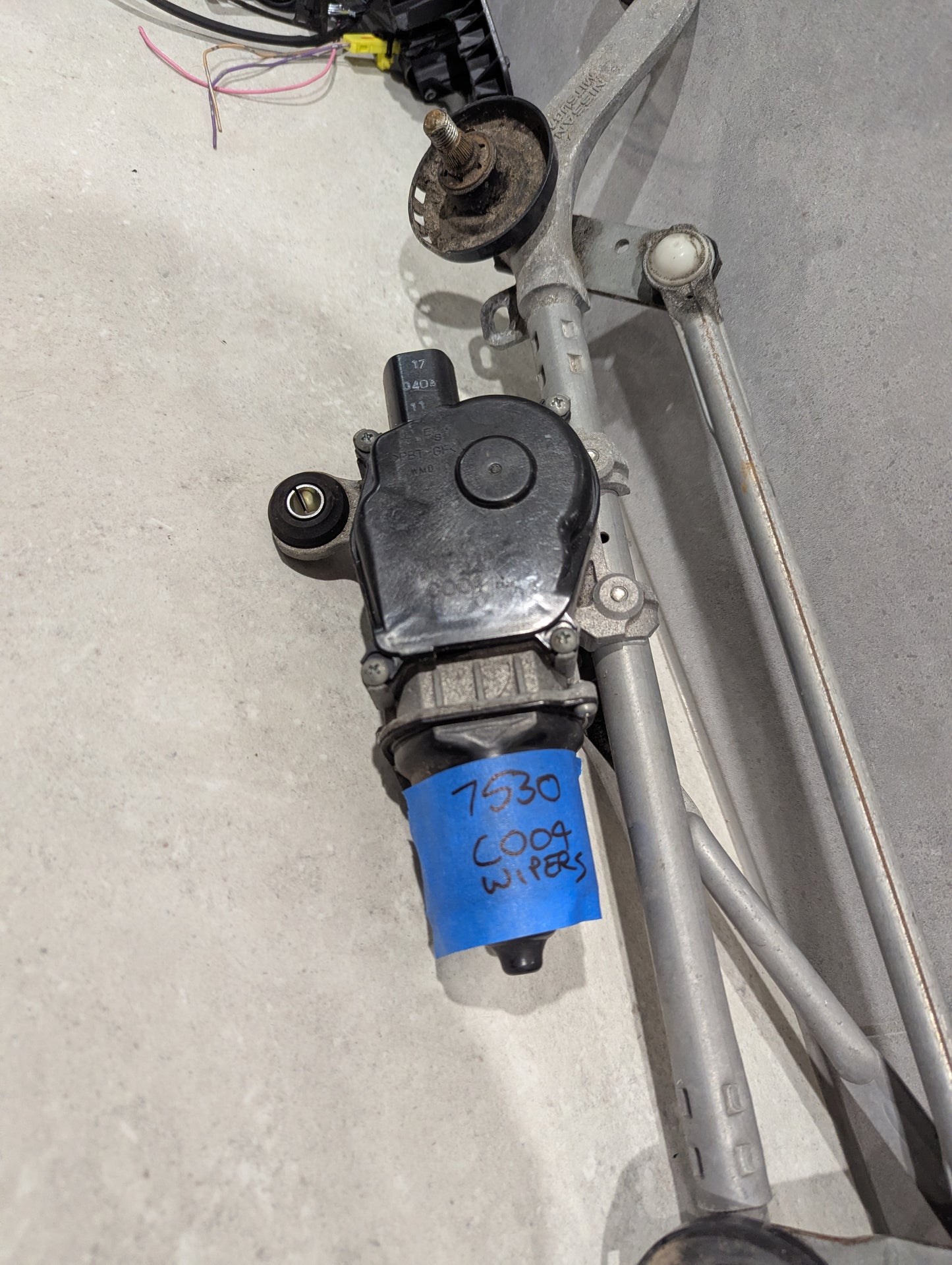 Close-up of wiper motor with blue label reading '7530 C004 WIPERS' attached to assembly