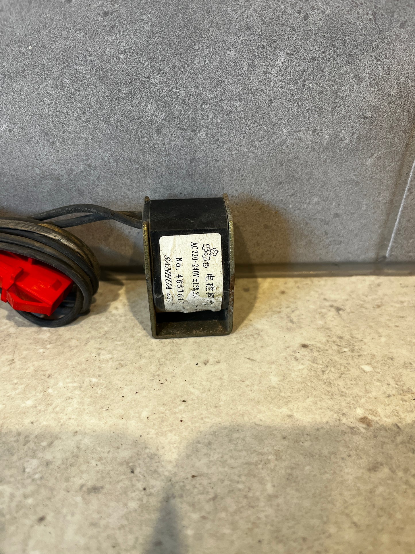 Close-up of electrical coil transformer with AC 220-240V label and red connector cable
