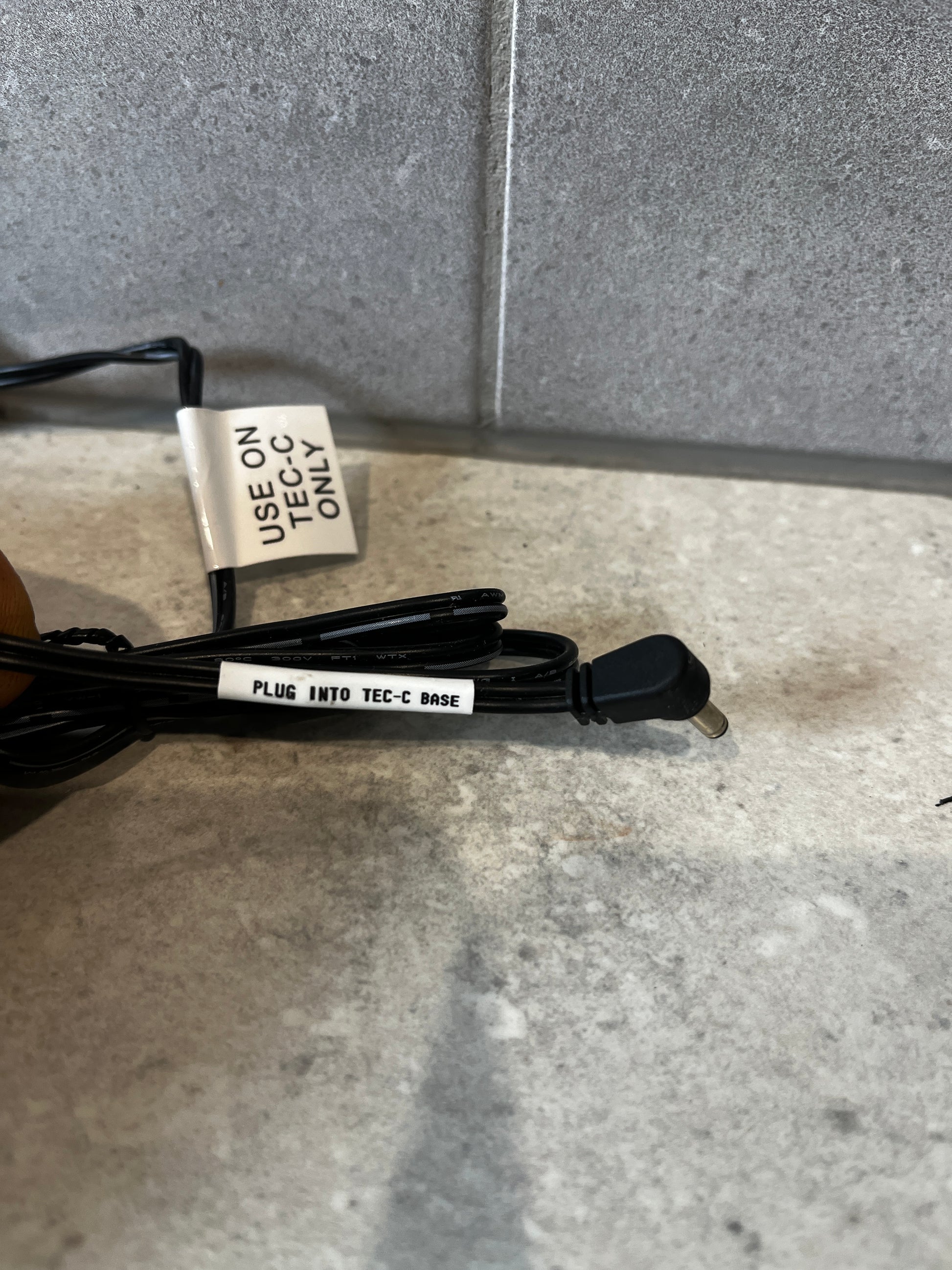 Close-up of TEC-C base adapter cable with label showing 'USE ON TEC-C ONLY' and 'PLUG INTO TEC-C BASE'