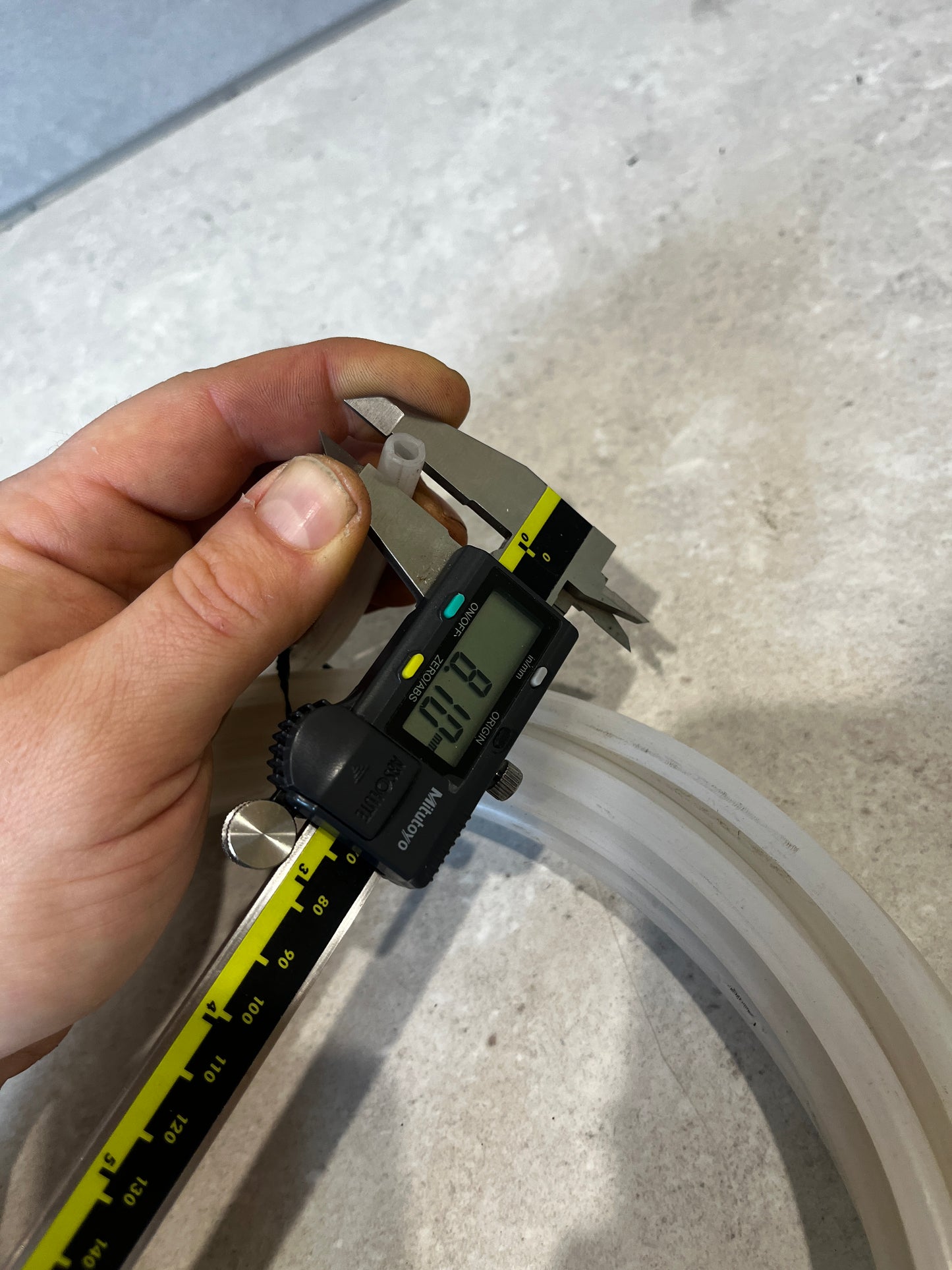 Person measuring inner diameter of silicone tubing with caliper