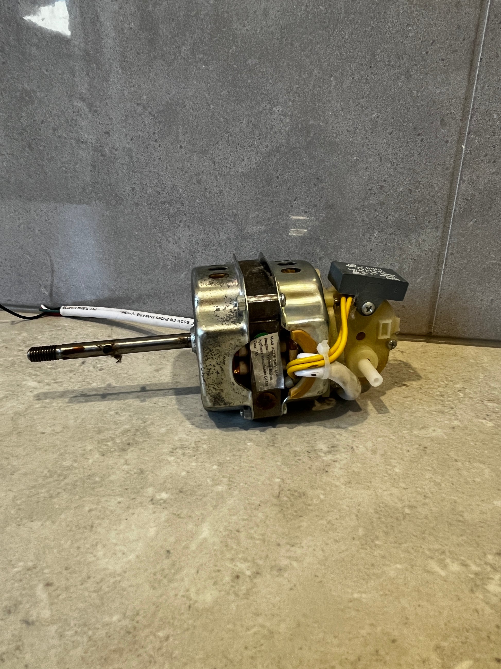 Side view of electric motor showing metal casing and wires on grey background