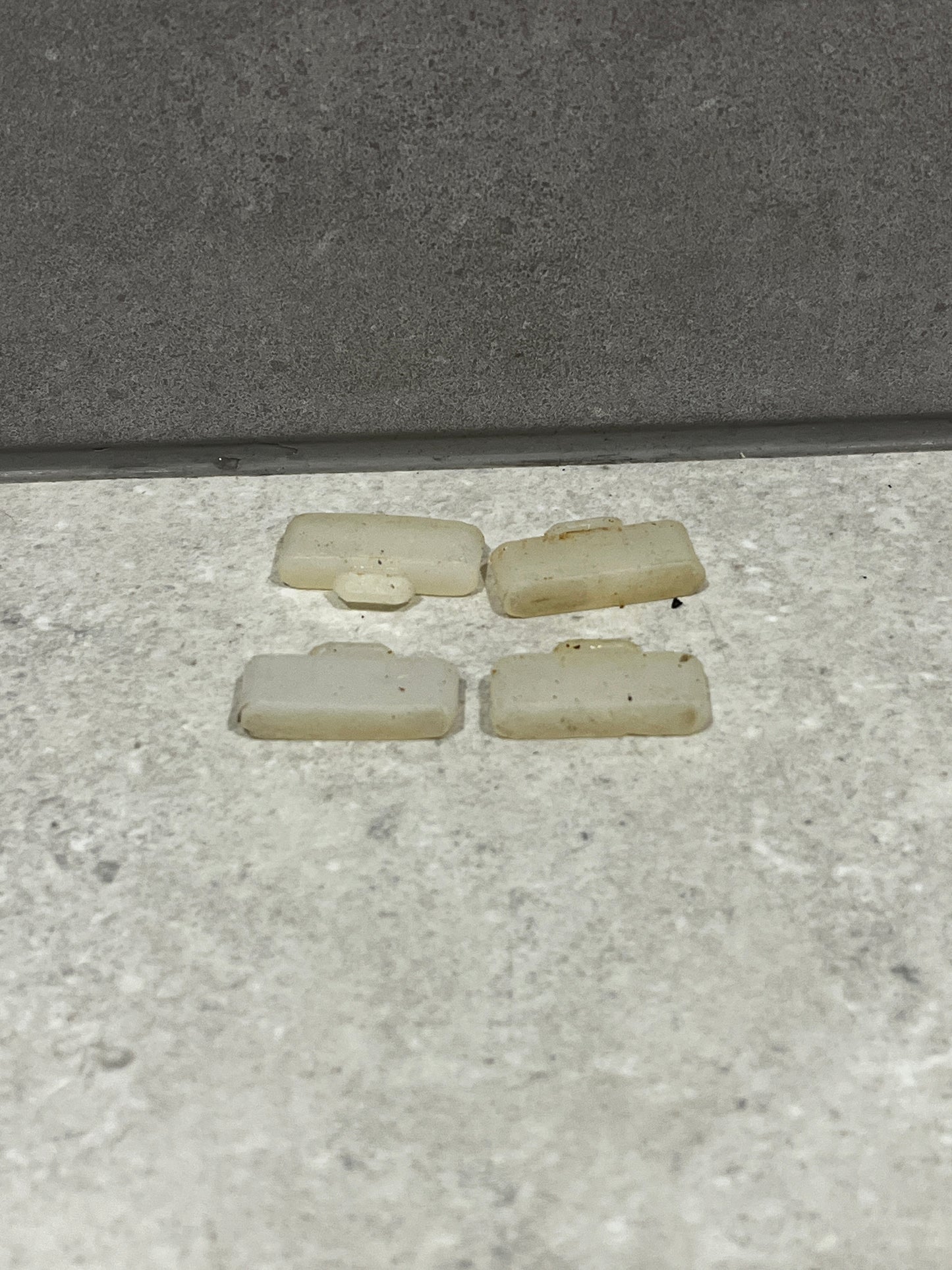 Four loose white plastic door stoppers placed on a floor surface