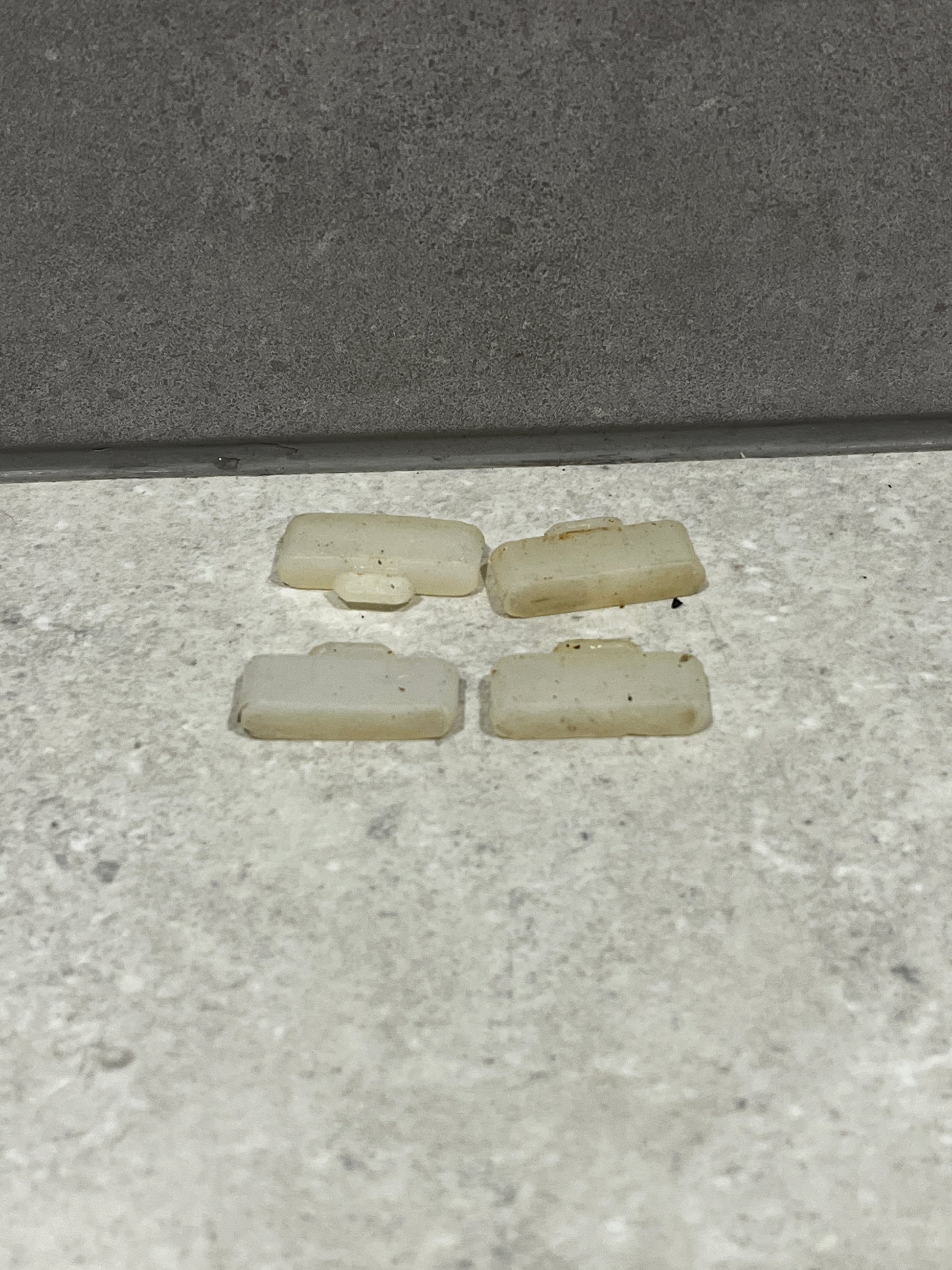 Four loose white plastic door stoppers placed on a floor surface