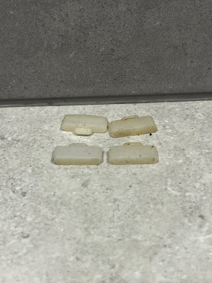 Four loose white plastic door stoppers placed on a floor surface