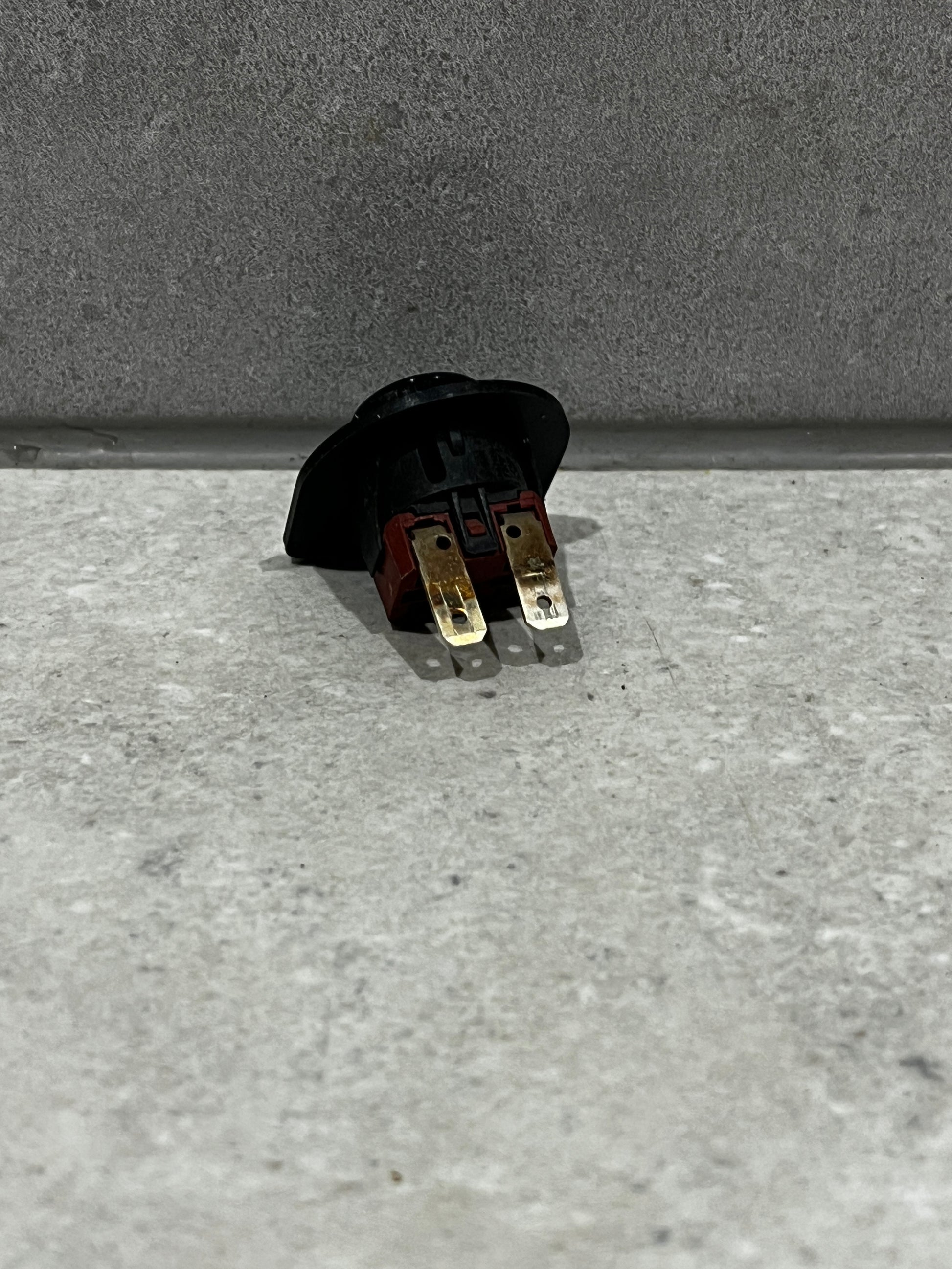 Rear view of round rocker switch showing two metal prongs