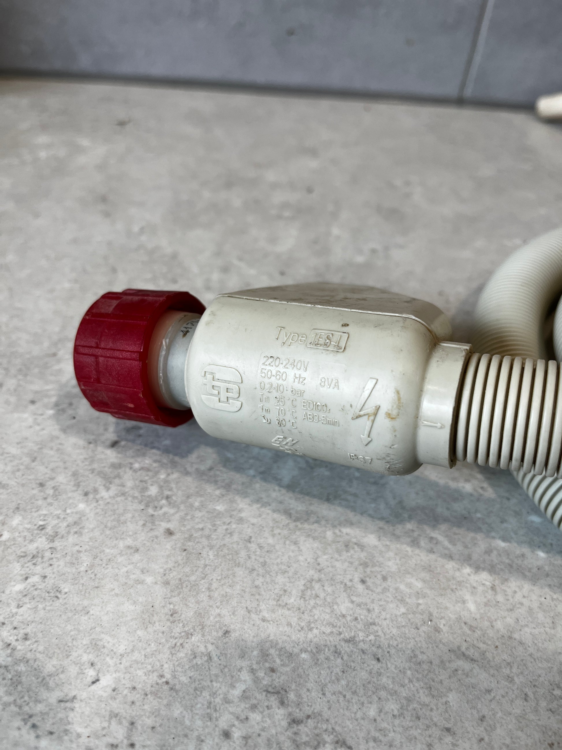 Close-up of electric valve on washing machine water inlet hose