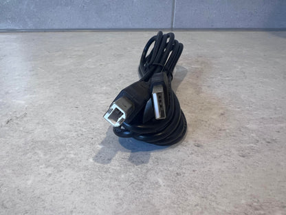 Close-up of USB A and USB B connectors of a black cable on a countertop