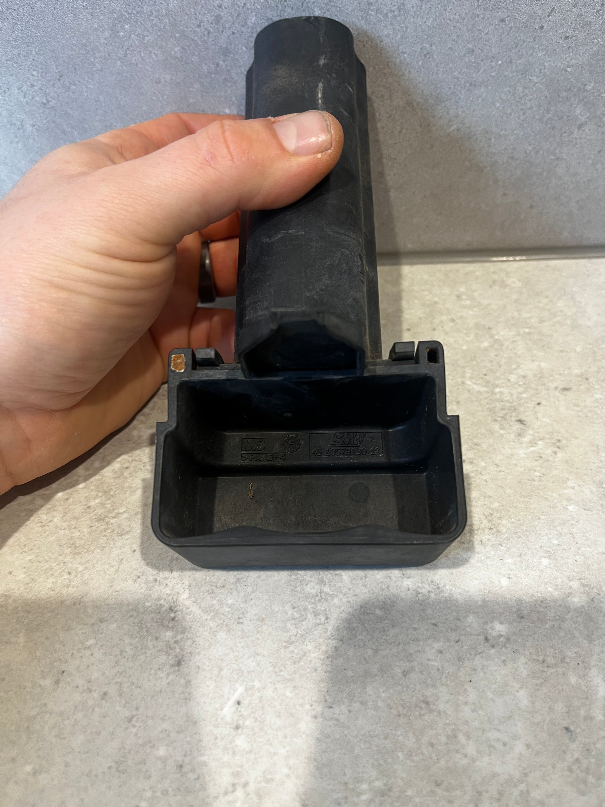 Close-up of the bottom side of black plastic electrical connector showing its open compartment and hand holding it