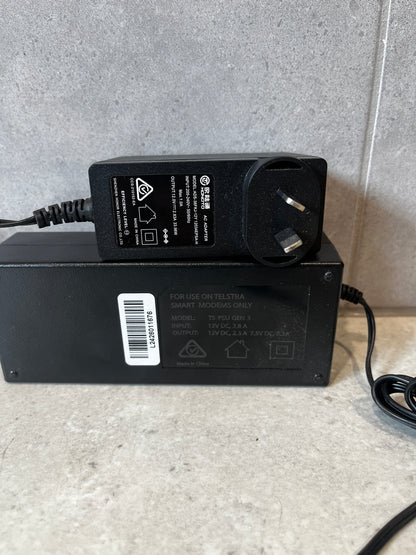 Close-up view of Telstra modem power adapters showing specifications