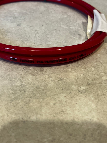 Close-up of red polyurethane tubing with material and size markings on concrete surface