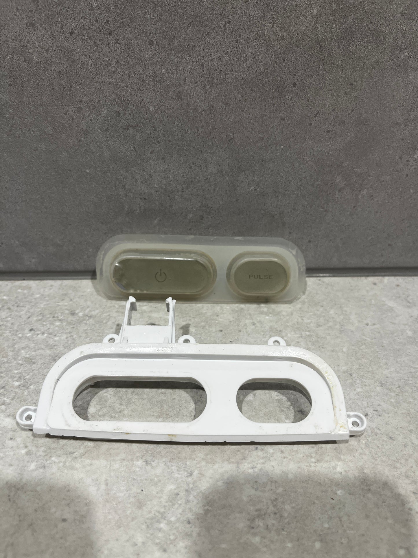 Close up of white blender control panel frame showing rectangular and oval cutouts for buttons