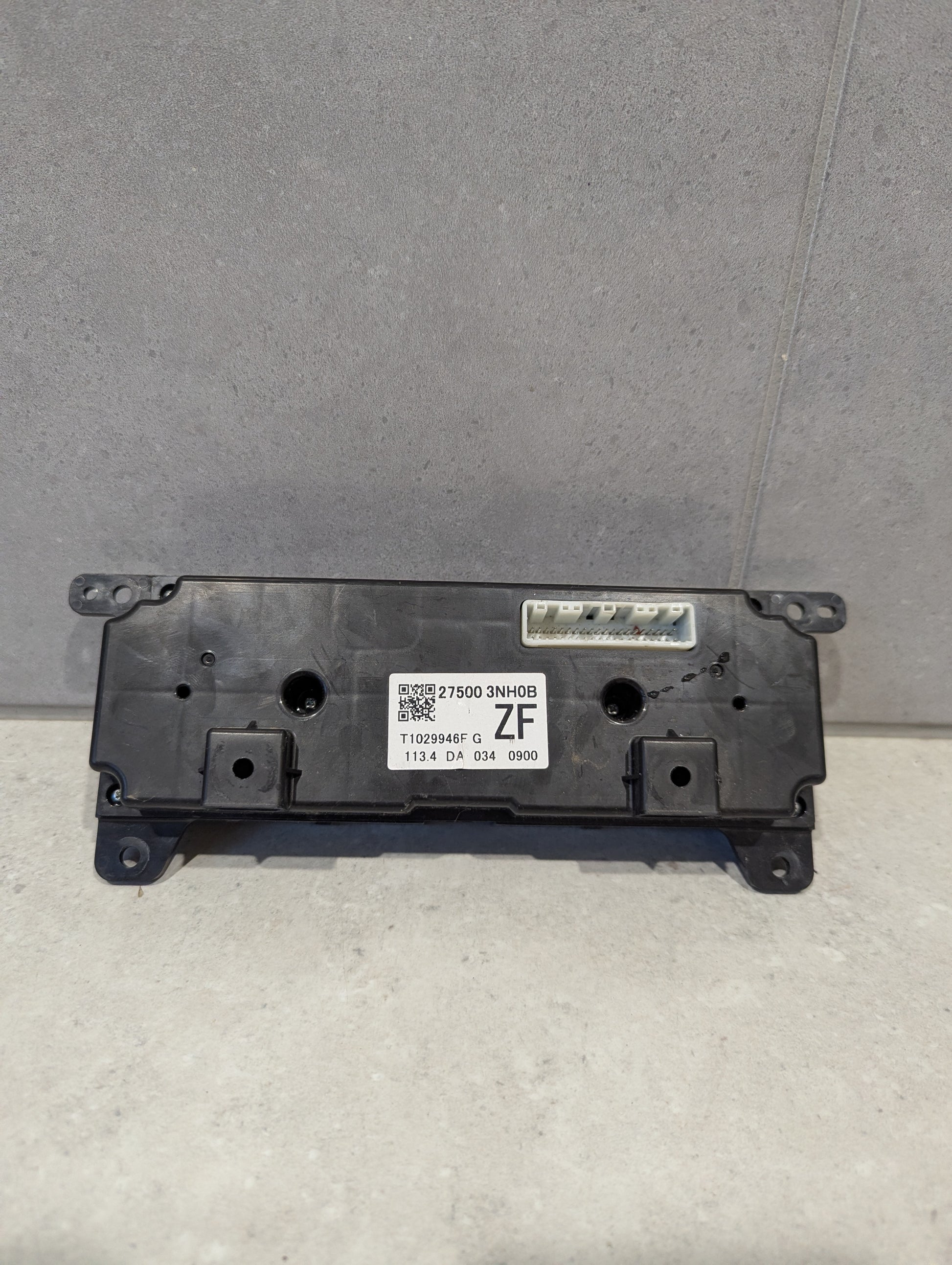 Rear view of automotive climate control panel assembly showing connector and product label