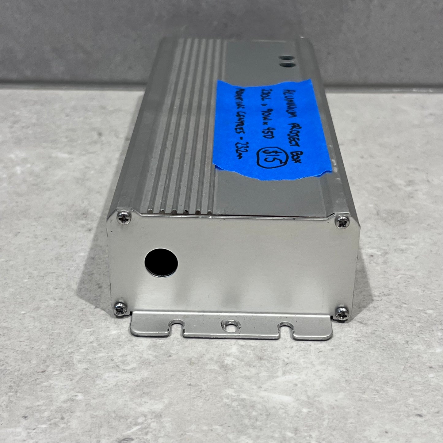 End view of aluminum project box displaying circular cutout and mounting brackets