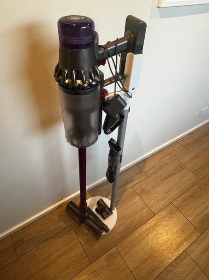 Close-up of Dyson vacuum with accessories mounted on the stand beside it