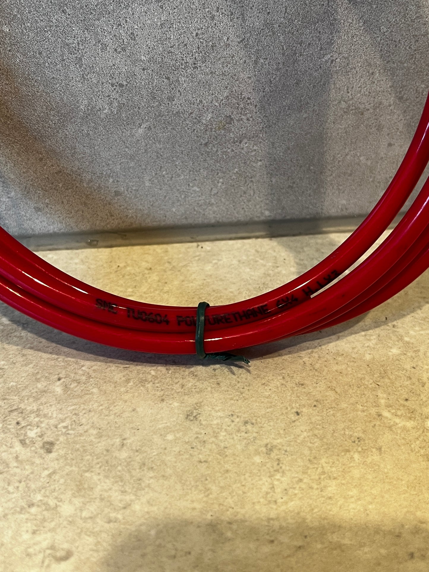 Close-up of red polyurethane tubing showing printed product details and flexible coil