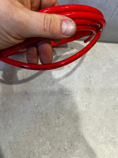 Close-up of red polyurethane tube held by hand showing smooth surface and text