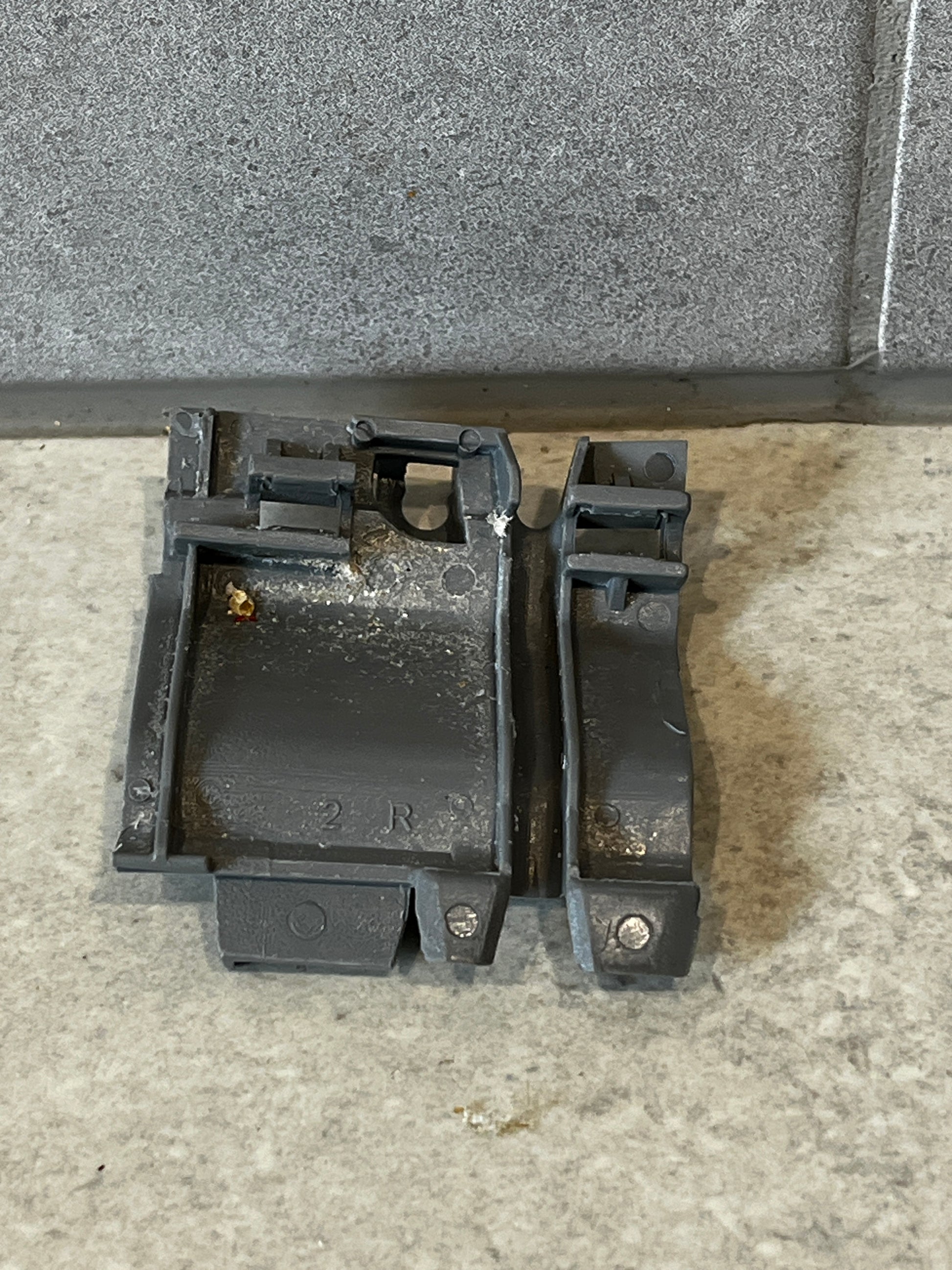 Gray plastic mechanical clip set on a light surface, rear view