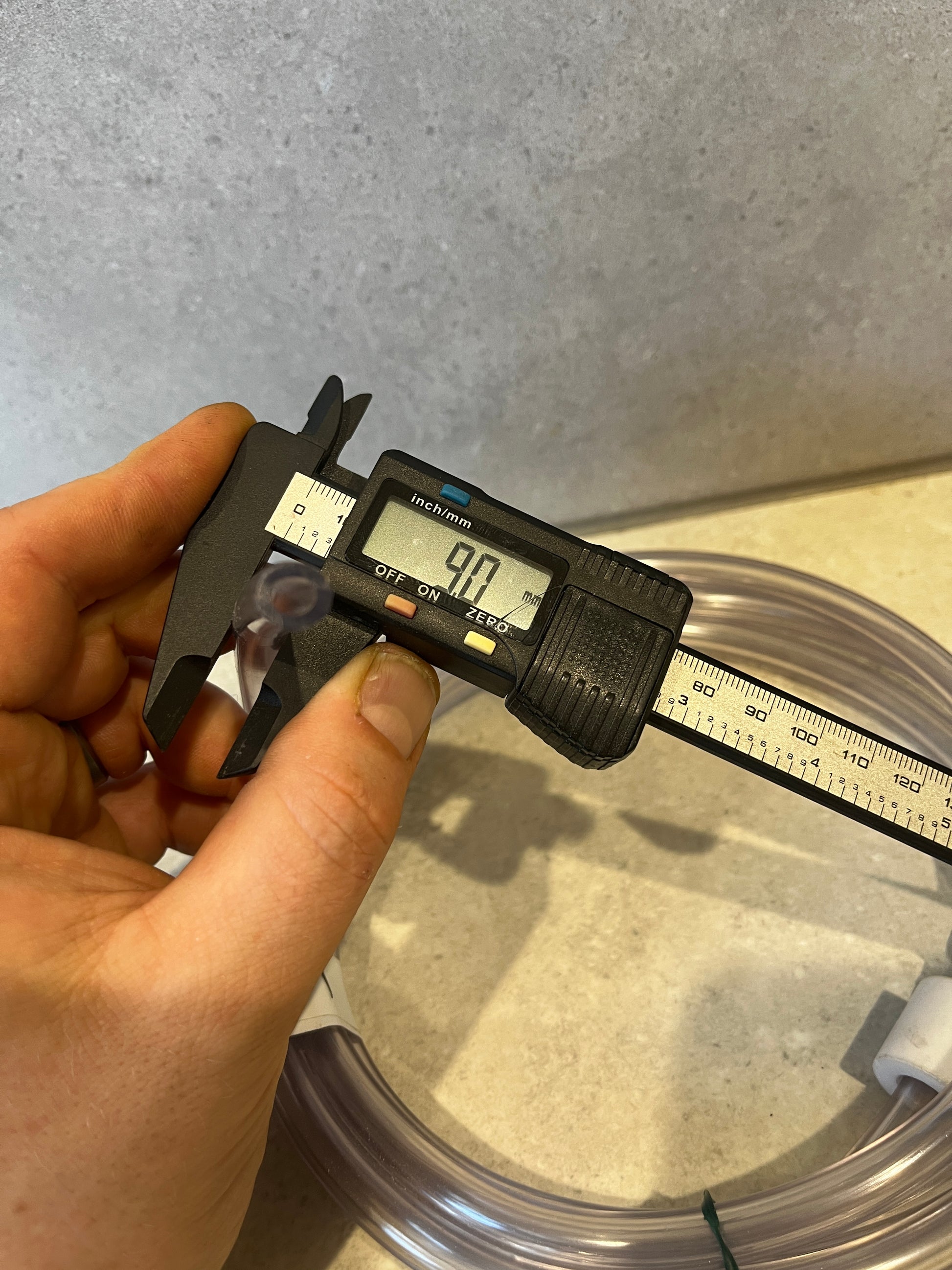 Measuring outer diameter of PVC tubing showing 9.0 millimeters on digital caliper