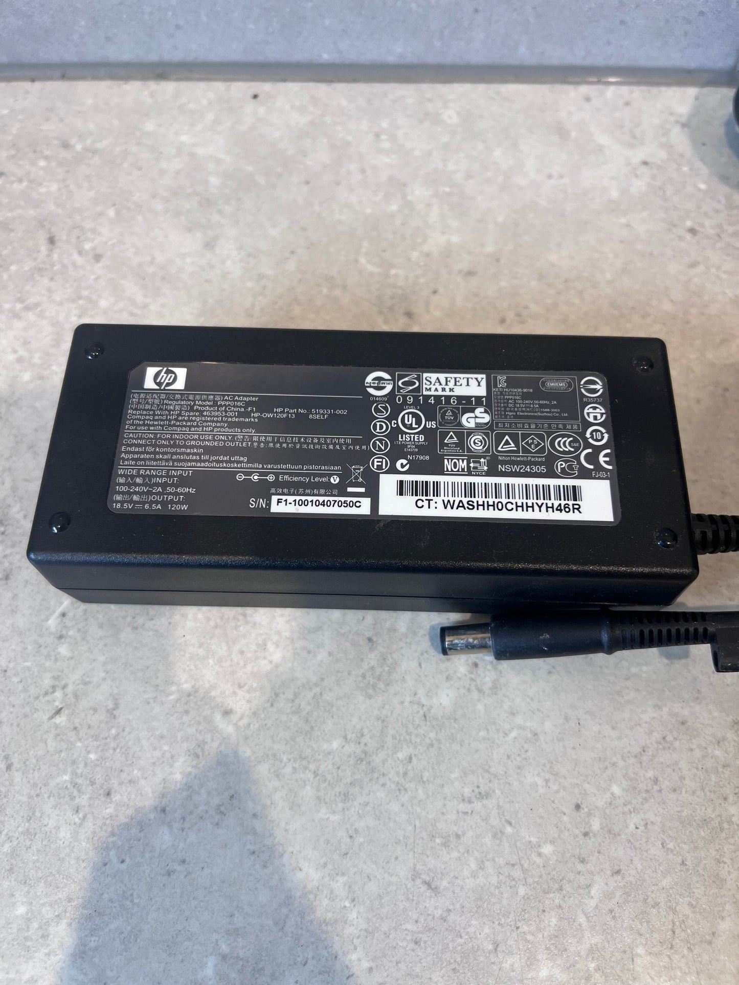 Close-up of HP 120W laptop power adapter showing label and connector