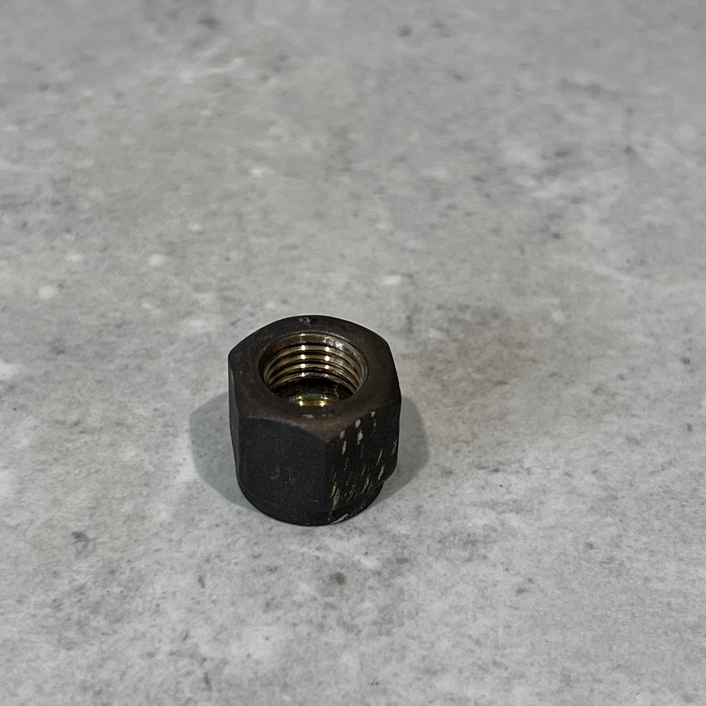 Close-up of a durable 1/4 inch metal flare nut on a neutral gray background for plumbing and HVAC use