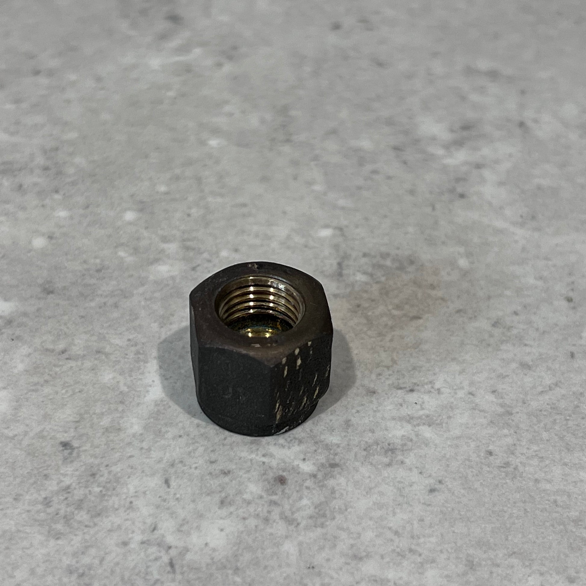 Close-up of a durable 1/4 inch metal flare nut on a neutral gray background for plumbing and HVAC use
