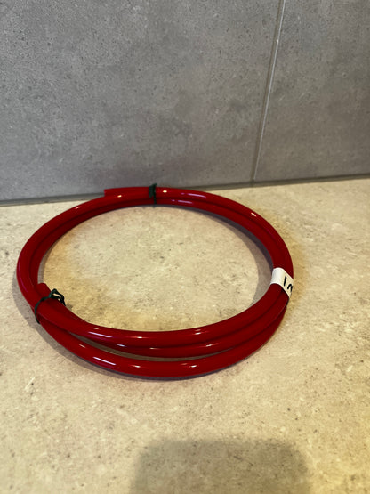 Red polyurethane tubing coil neatly coiled on flat surface