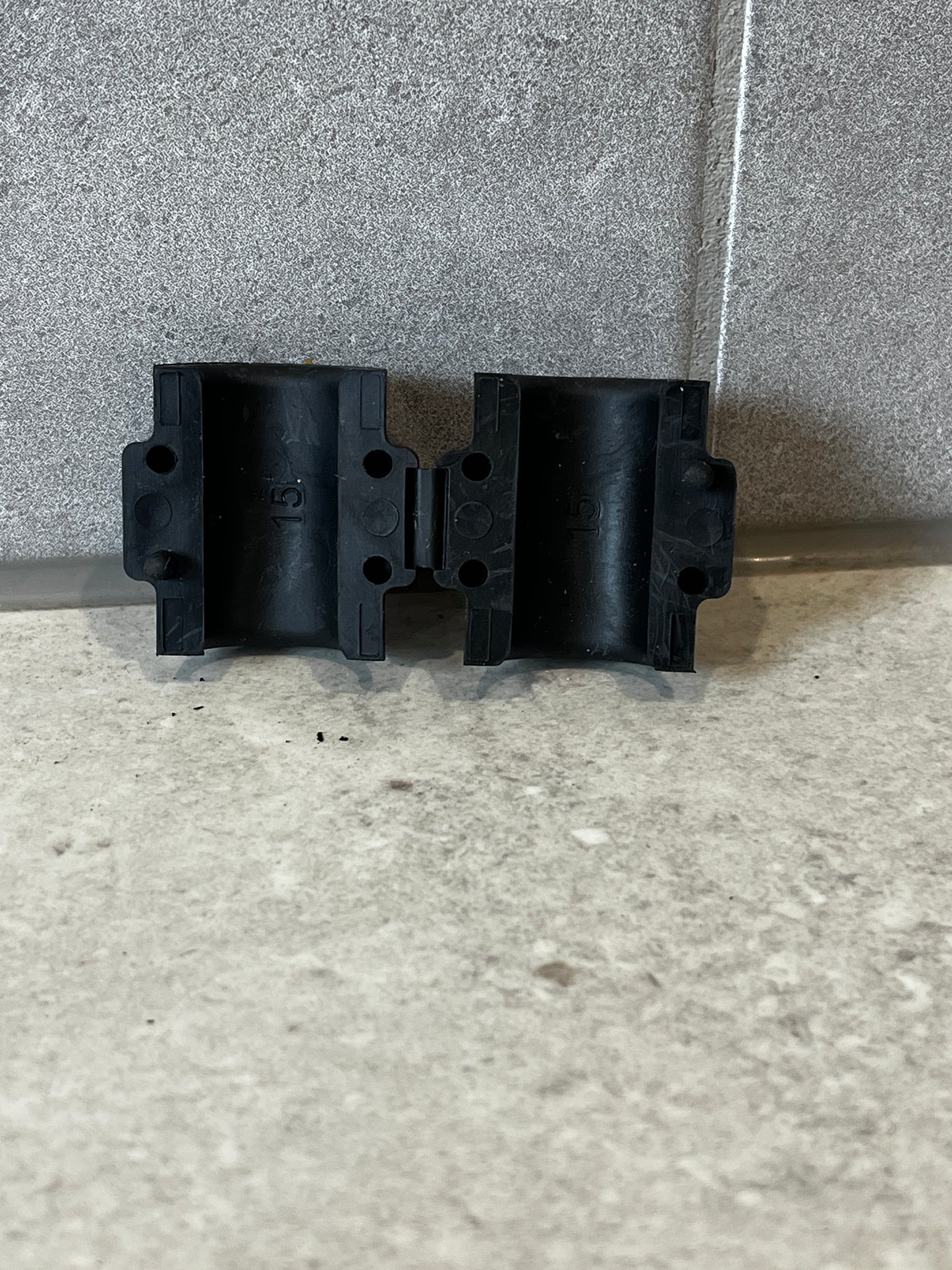 Front view of two black 15mm pipe clamps showing mounting holes