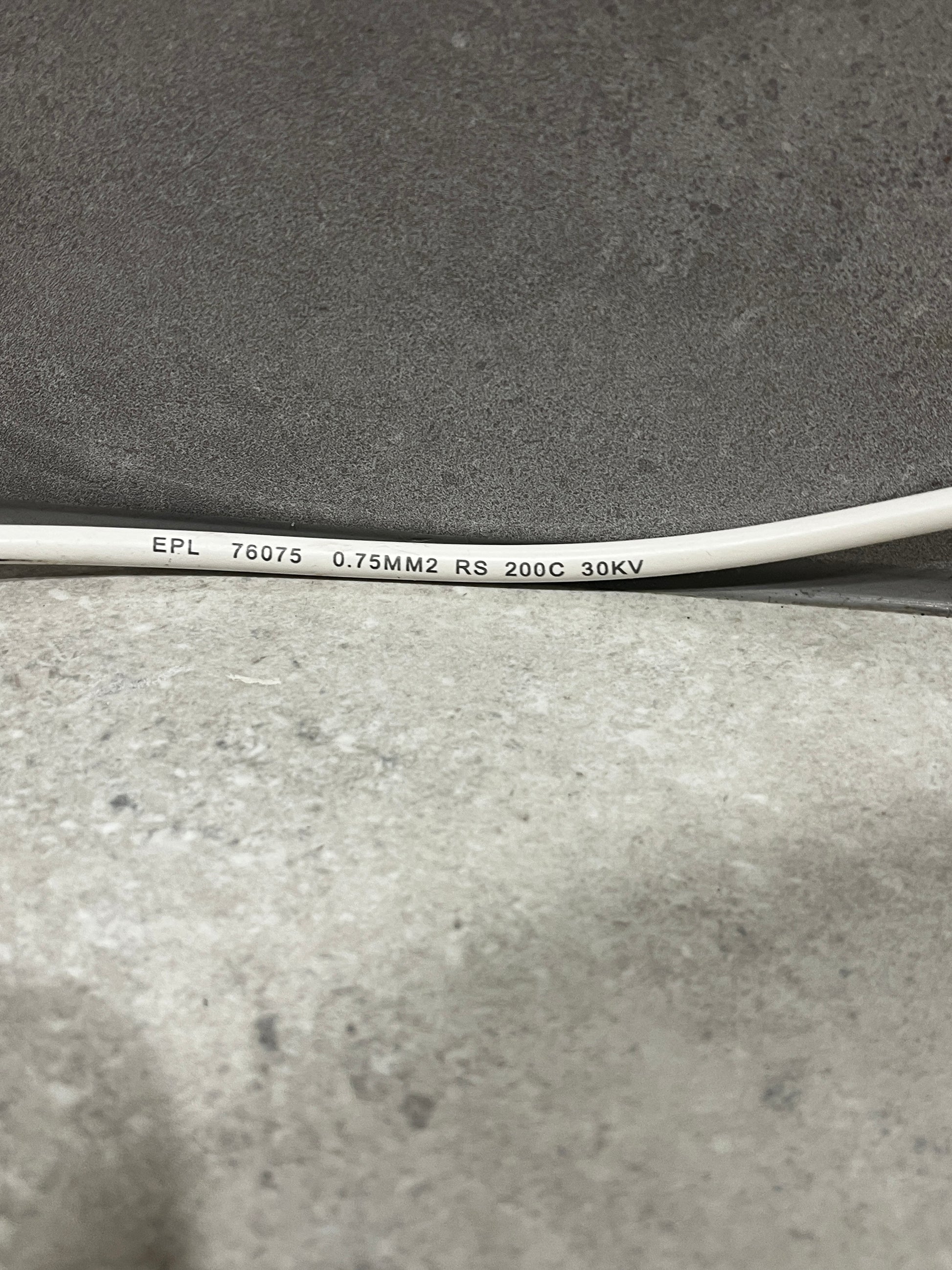 Close-up of white electrical wire showing printed specifications: EPL 76075 0.75MM2 RS 200C 30KV