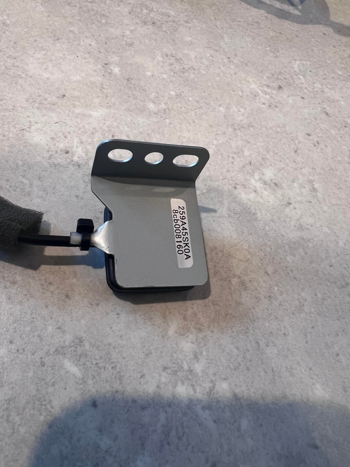 Close-up of automotive wire harness metal mounting bracket with label