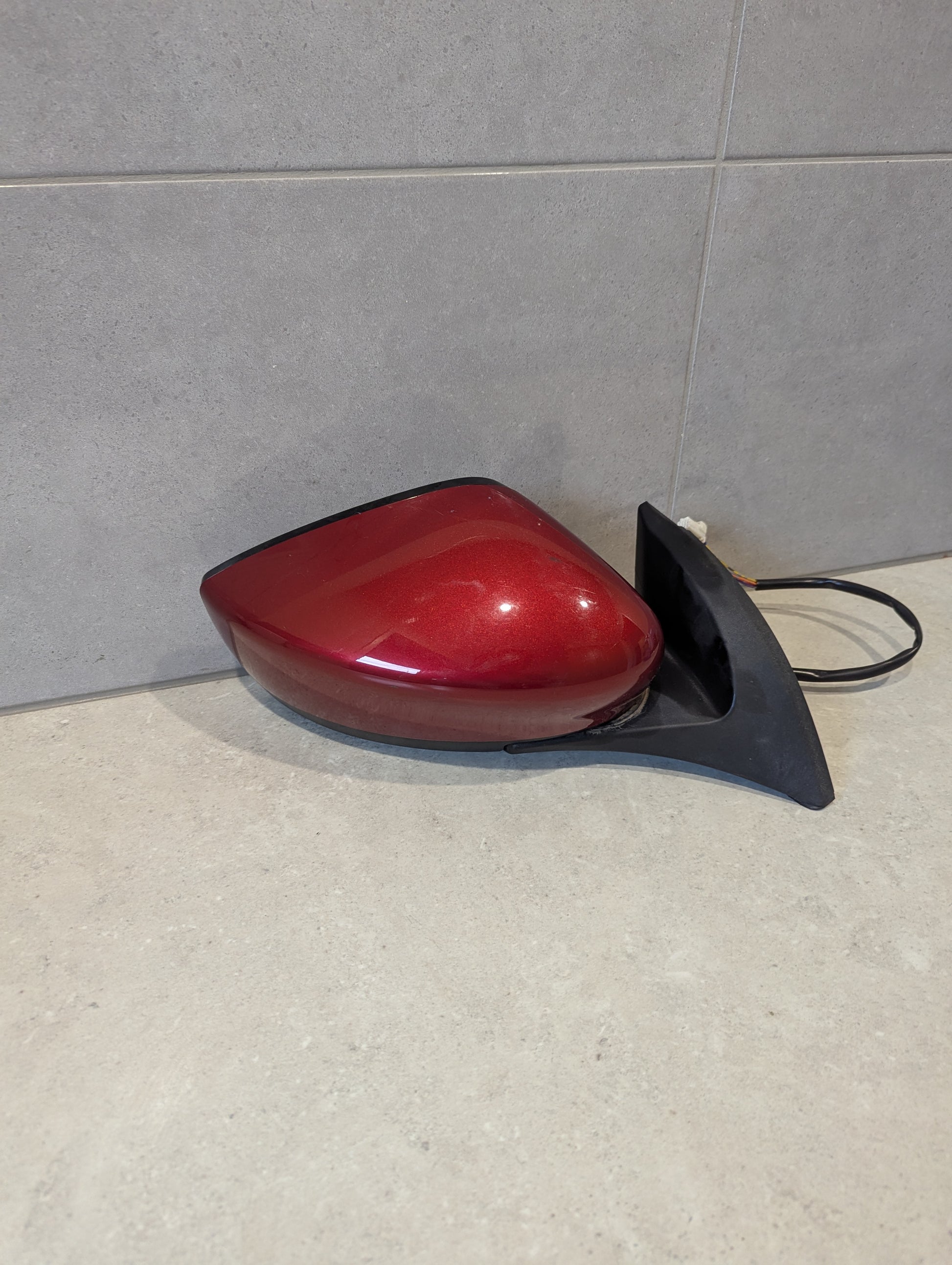 Rear view of red right side car mirror assembly with black mount