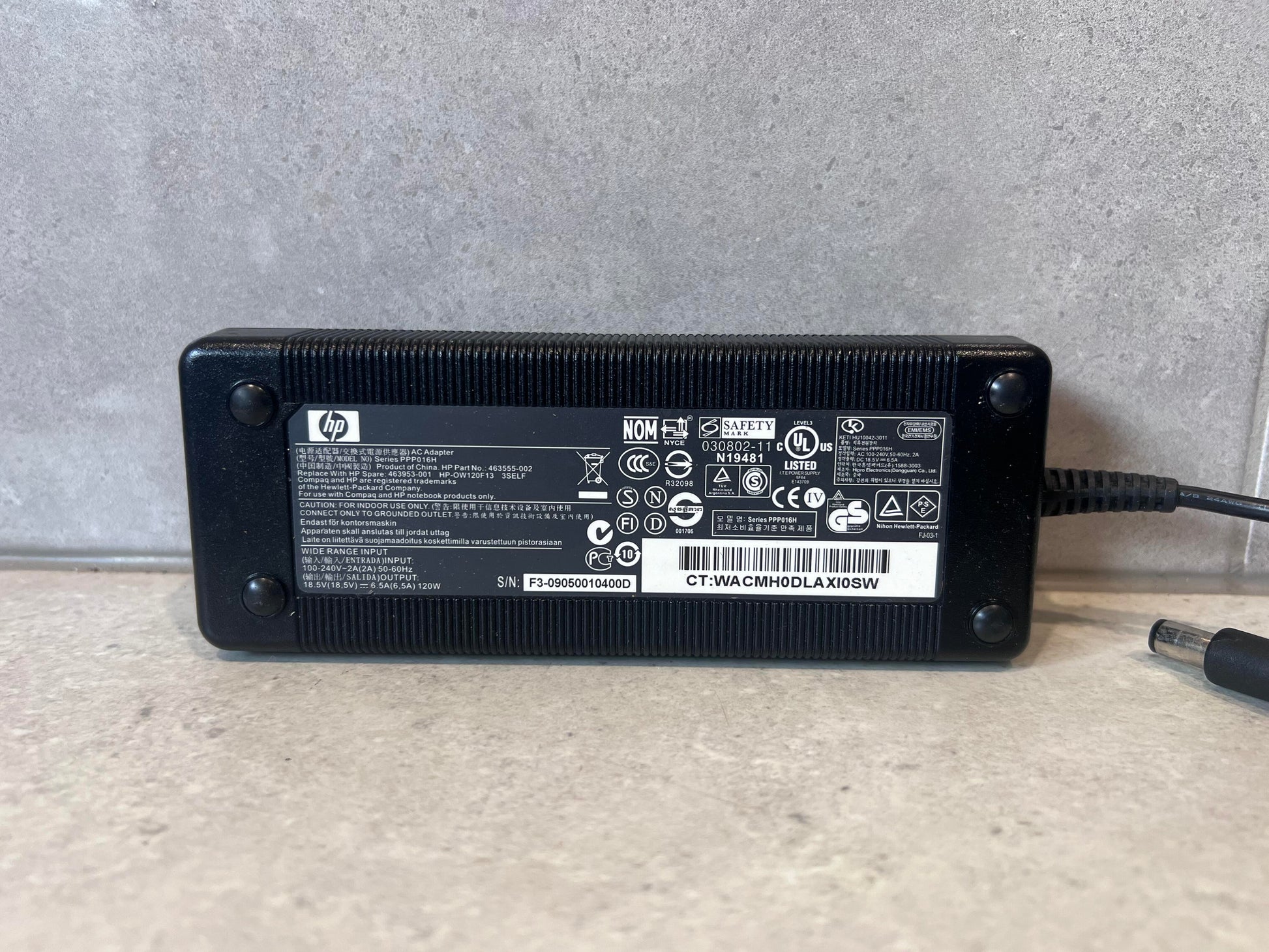 Close-up of HP 120W laptop power adapter showing label and specifications