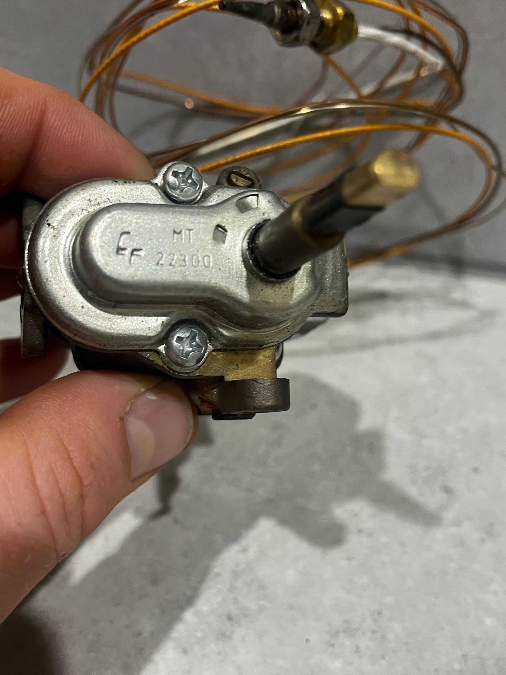 Close-up of gas oven thermostat control valve showing metal components and coil