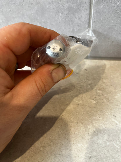Close-up view of metal nozzle fitting with visible engravings in a plastic bag