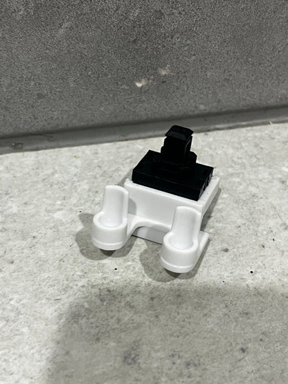 Side angle view of compact push button switch showing actuator and base design