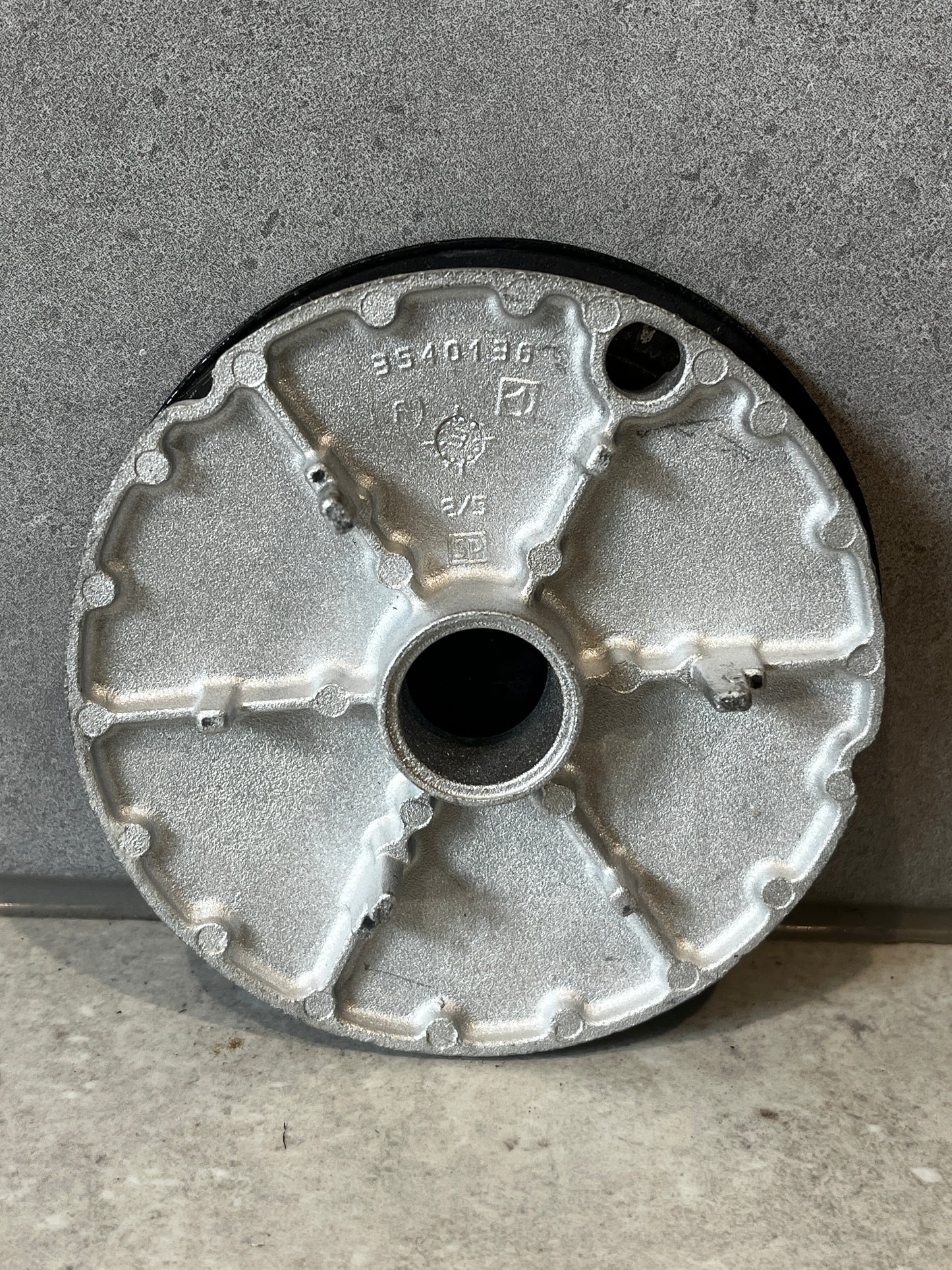 Bottom view of metal access cover plate showing structural ridges and center opening