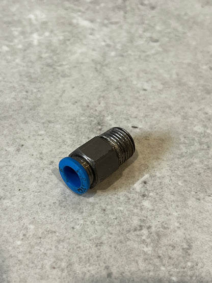 Metal push-to-connect pneumatic fitting with blue ring on gray surface angled view
