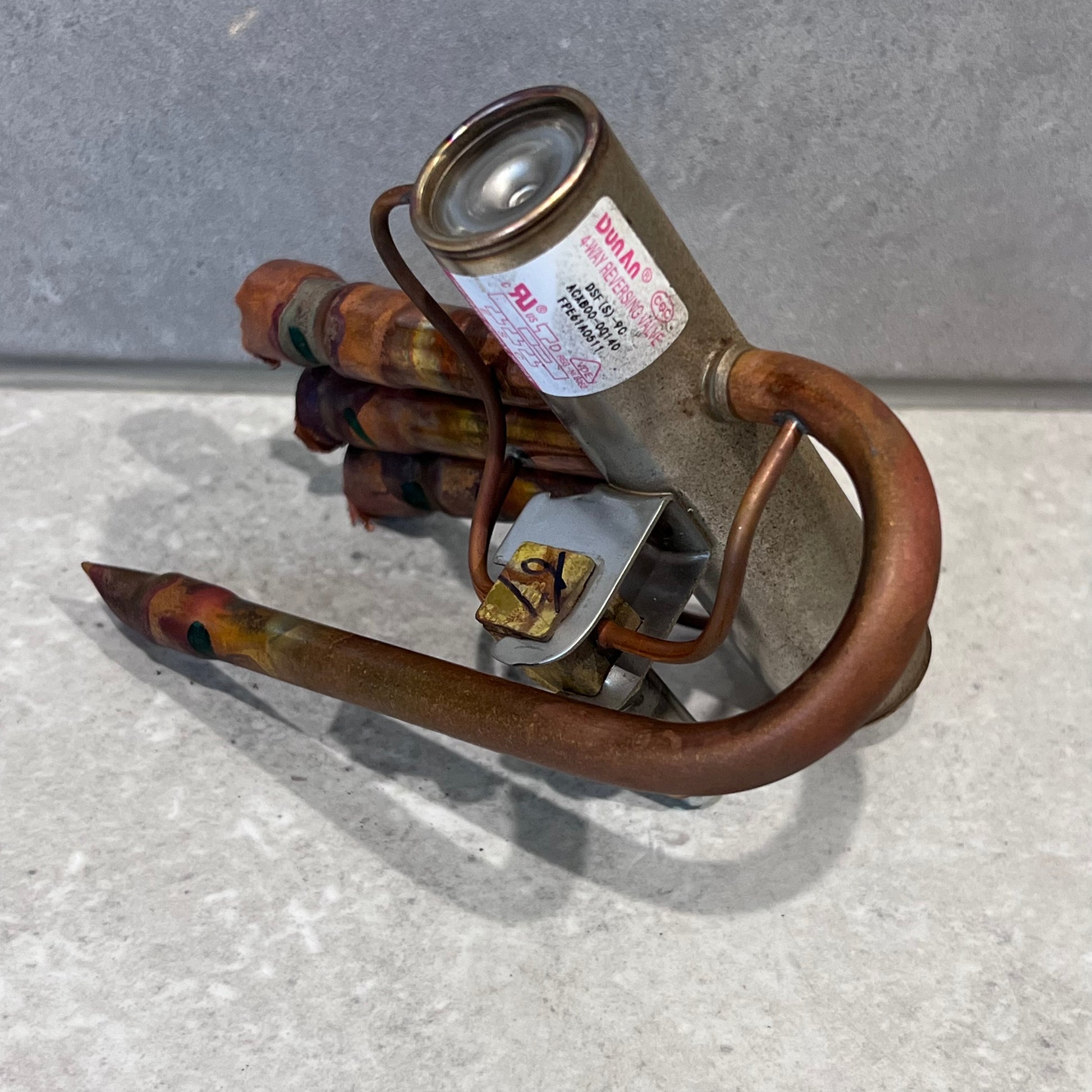 Close-up of Dunlab 4-way HVAC reversing valve's metal and copper construction with visible label.