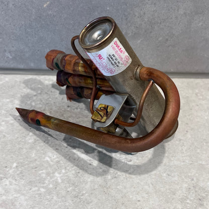 Close-up of Dunlab 4-way HVAC reversing valve's metal and copper construction with visible label.